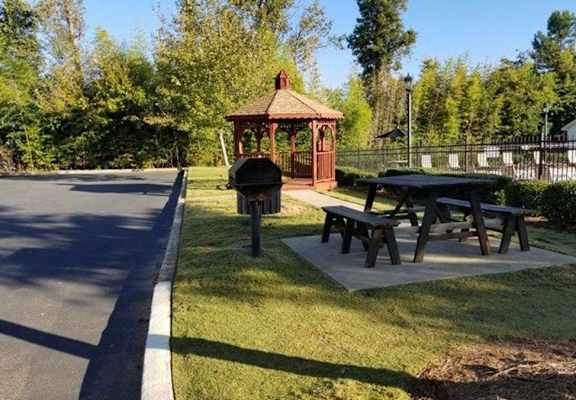 A gazebo sits next to a picnic table in a park.