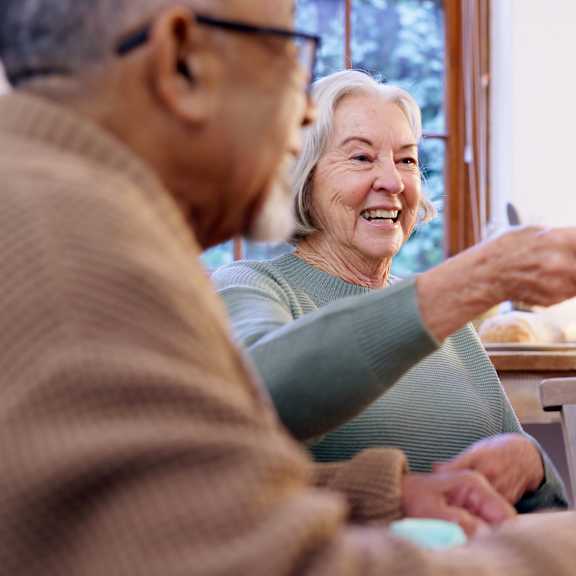 Three elderly people are sitting at a table, enjoying a meal and each other's company.