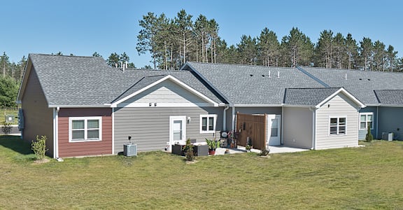 A house with a red door is surrounded by other houses and trees.