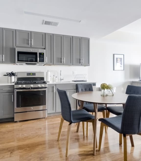 an open kitchen and dining area with gray cabinets and a wooden floor