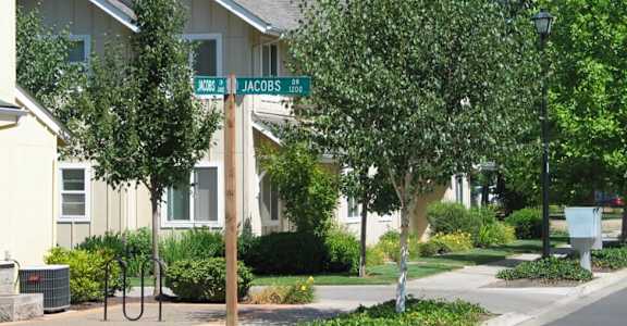 A street sign for Jacobs street is in front of a house.