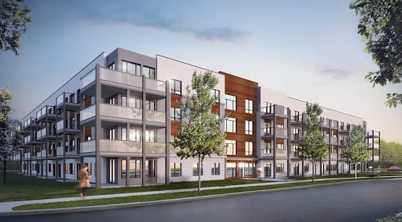 A woman walks past a modern apartment building.