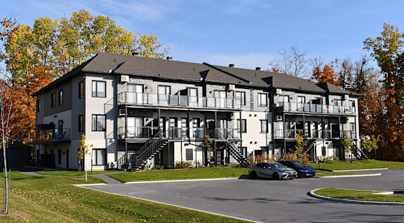 A large white building with a black roof and a balcony on the second floor.
