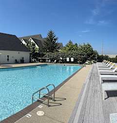 A large swimming pool with lounge chairs and a building in the background.