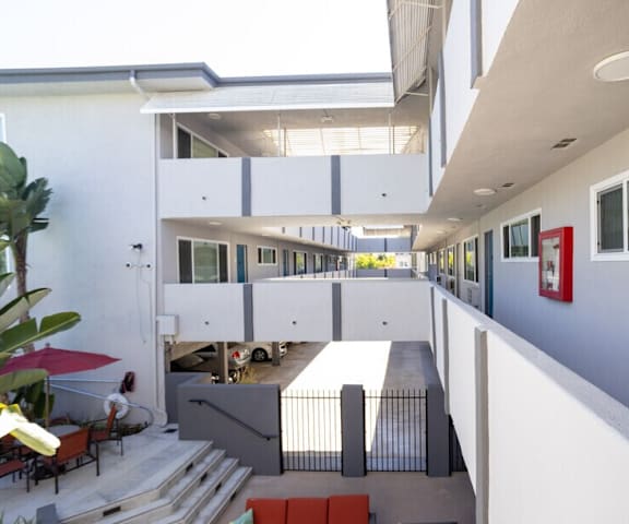 A white building with a red umbrella and a red bench.