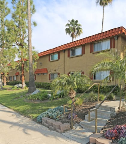 A house with a red tile roof is surrounded by greenery.