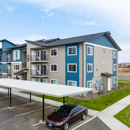 a row of new apartment buildings with cars parked in a parking lot