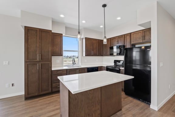 a kitchen with a large island and a black refrigerator