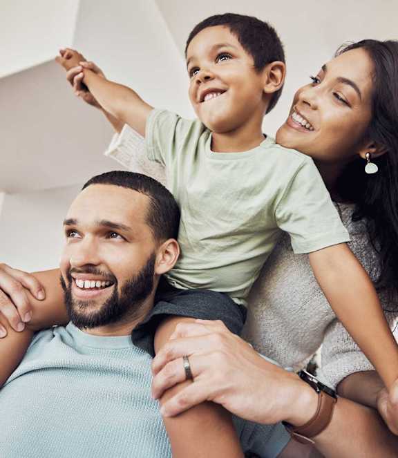 A family of three is sitting closely together, sharing a joyful moment.