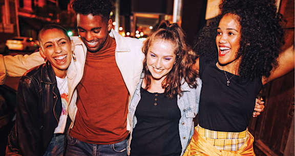 Four people are standing close together and laughing.