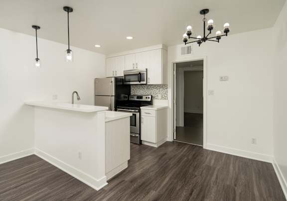 A kitchen with a white counter and a chandelier.