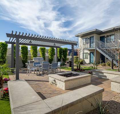 A patio area with a table and chairs under a pergola.