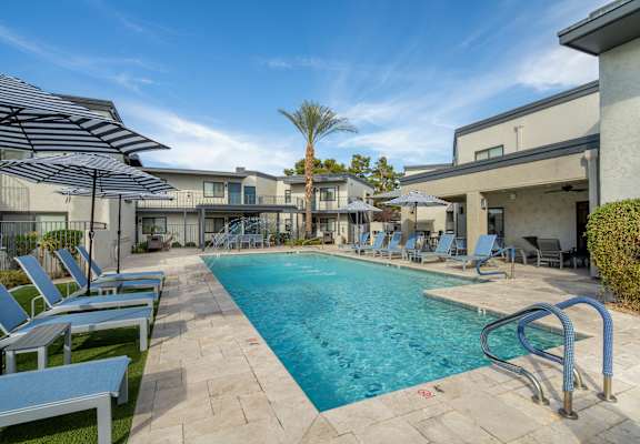 A swimming pool surrounded by lounge chairs and umbrellas.