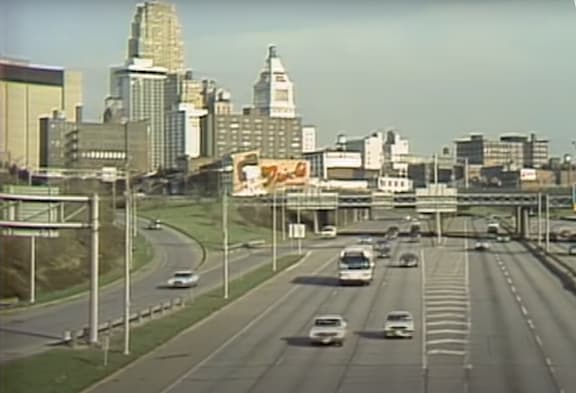 A highway with cars and a city skyline in the background.