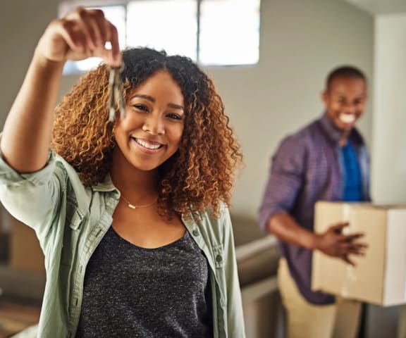 a woman is holding up her hair in a room with a man holding a box
