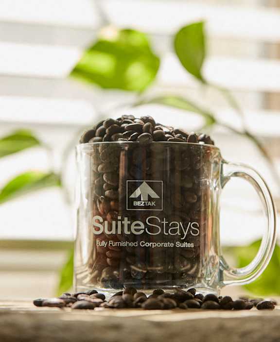 A glass mug filled with coffee beans and the words SuiteStays on it.