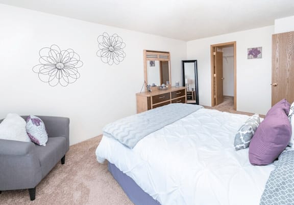 A bedroom with a bed, a chair, and a dresser.