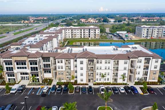 A large apartment complex with a parking lot in front.
