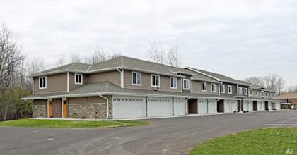 A long building with a parking lot in front.
