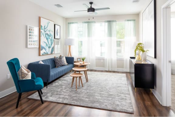 A living room with a blue couch, a wooden table, and a ceiling fan at 19 South Apartments in Kissimmee, FL