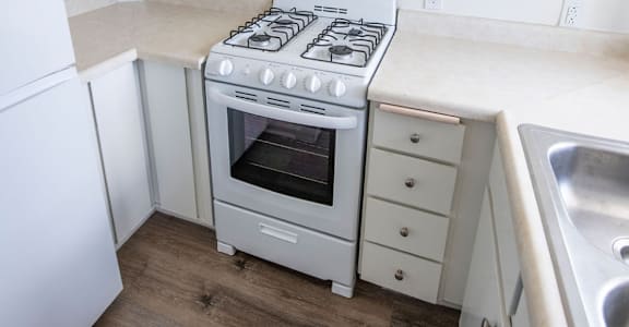 A white kitchen with a stove top oven and white cabinets.