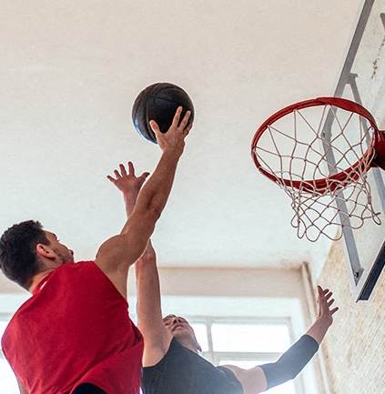 Two men playing basketball in a room.