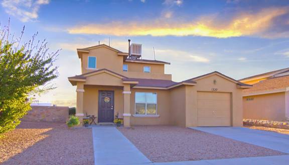A house with a brown door and a driveway in front.