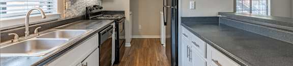 a kitchen with white cabinets and black counter tops