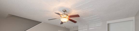 an empty living room with a fireplace and a ceiling fan