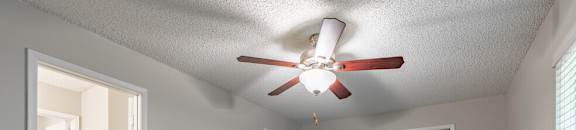 an empty living room with a ceiling fan and a closet