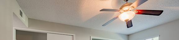 an empty living room with a ceiling fan and a closet
