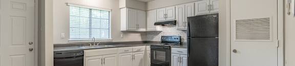an empty kitchen with white cabinets and black appliances