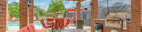 a covered patio with a grill and a table with chairs