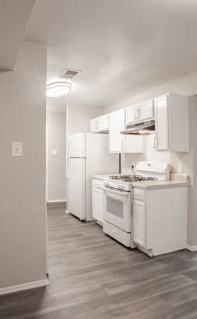 an empty kitchen with white appliances and a wood floor