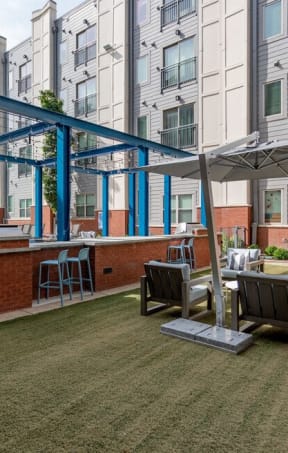 a patio with tables and chairs and a bar in front of an apartment building
