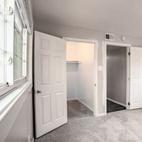 an empty bedroom with white doors and a closet