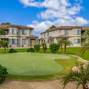 A golf course is in front of apartment buildings.