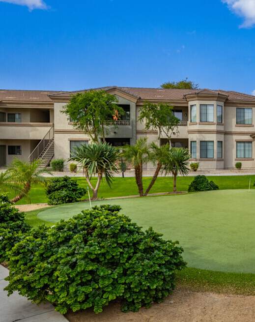 A golf course is in front of apartment buildings.