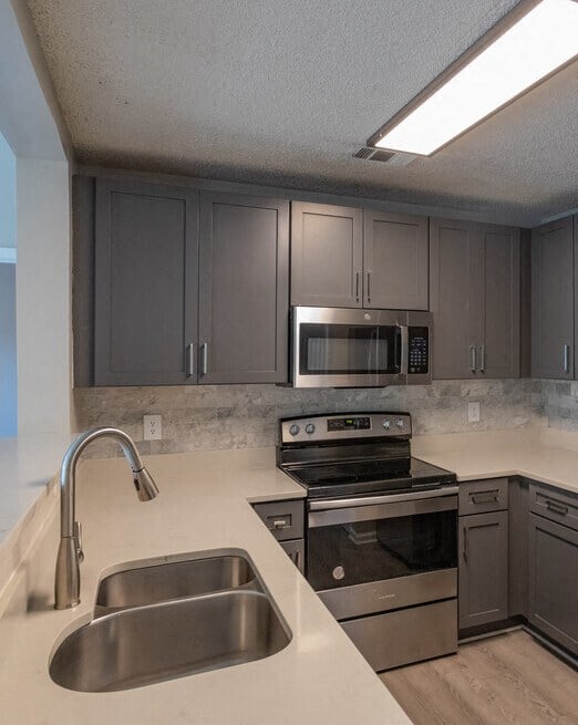 a kitchen with gray cabinets and white countertops