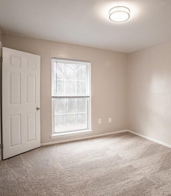 an empty bedroom with a white door and a window