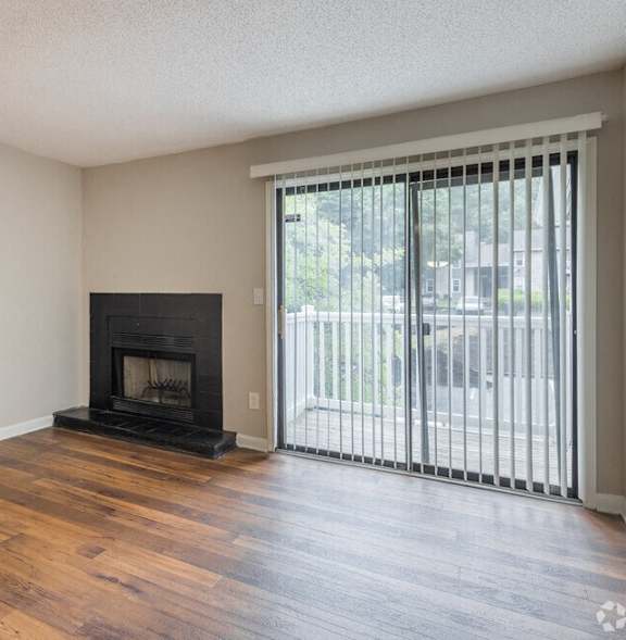 an empty living room with a fireplace and a sliding glass door