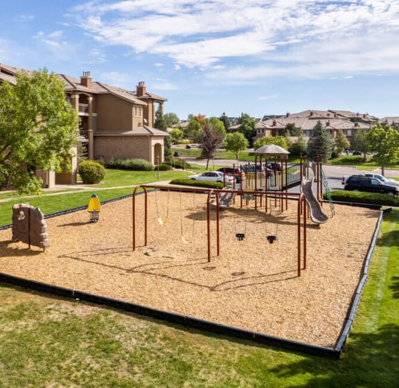 a playground in the middle of a park with houses in the background