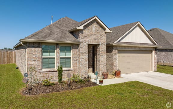 a brick house with a brown roof and a driveway
