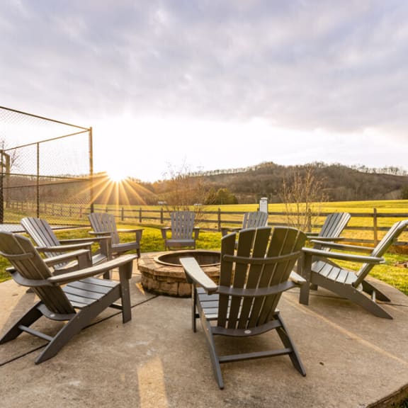 a patio with rocking chairs and a fire pit