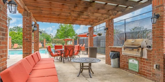 a covered patio with a grill and a table with chairs