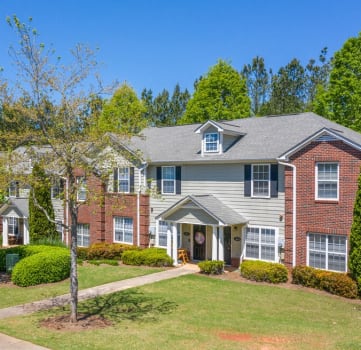 a house with a lawn and trees in front of it
