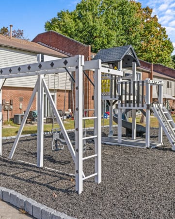 a playground with a swing set in front of a house