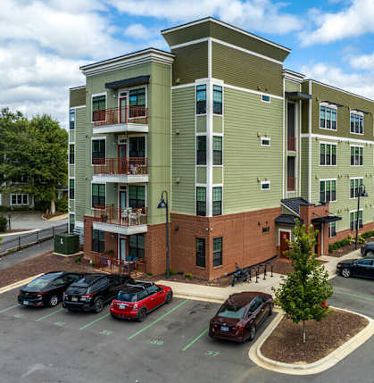 a large apartment building with cars parked in a parking lot