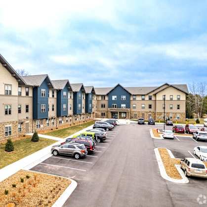 an exterior view of an apartment complex with cars parked in a parking lot