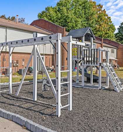 a playground with a swing set in front of a house